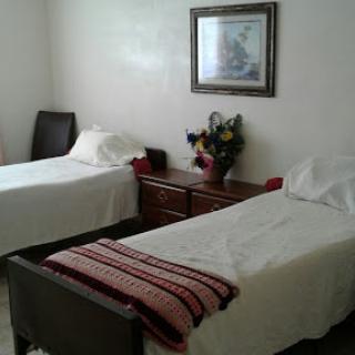 A cozy bedroom featuring two neatly made twin beds, a wooden dresser, and decorative elements.
