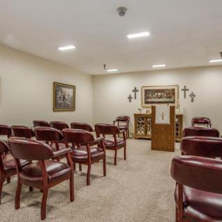 A small, well-lit chapel interior with rows of chairs facing an altar.