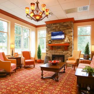 A cozy living room with elegant furniture and a stone fireplace, illuminated by a chandelier.