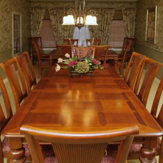 A well-decorated dining room with a wooden table and chairs, featuring a central floral arrangement and a chandelier overhead.