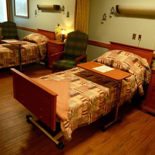 A hospital room with two patient beds and bedside tables.
