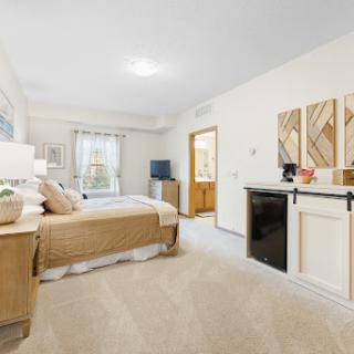 A spacious and cozy bedroom featuring modern interior design, complete with a king size bed and a mini fridge.