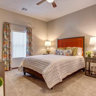A cozy bedroom with a neatly made bed, bedside lamps, and floral curtains.
