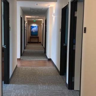 A long office hallway with multiple doors and carpeted flooring.