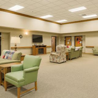 A spacious and cozy lounge area featuring green chairs and soft lighting.
