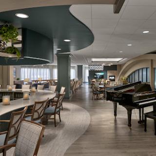 A modern lounge area featuring a piano, curved design elements, and comfortable seating.