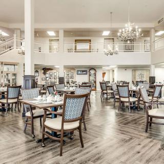 A spacious and elegantly designed dining room with tables and chairs under a chandelier.