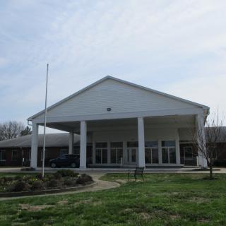 A large building with a columned entrance and a grassy area in the foreground.