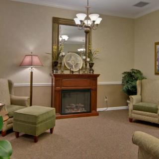 A cozy living room with a fireplace, elegant seating, and a large mirror above the mantel.