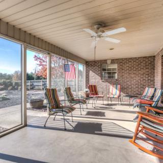 A spacious sunroom featuring an array of chairs, a ceiling fan, and large windows offering plenty of natural light.