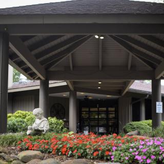 A building entrance with a garden featuring colorful flowers and a statue.