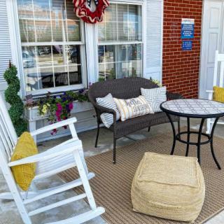 Cozy porch with a rocking chair, bench, and table set for relaxation.