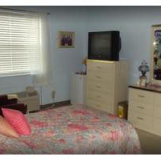 A cozy bedroom with a floral bedspread, dresser, and television.