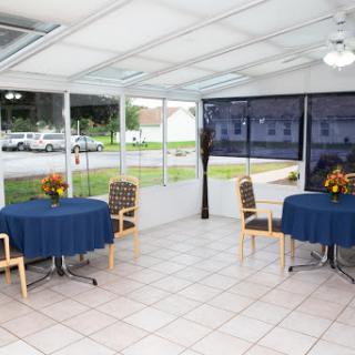 A cozy sunroom dining area with blue tablecloths and a bright atmosphere.