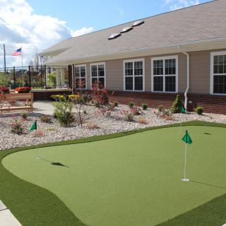 An outdoor putting green next to a building, providing a space for recreation and relaxation.