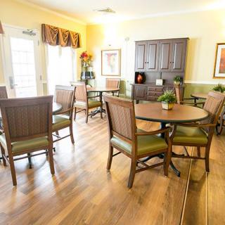 A well-lit dining room with wooden tables and chairs, featuring tasteful decor and flooring.
