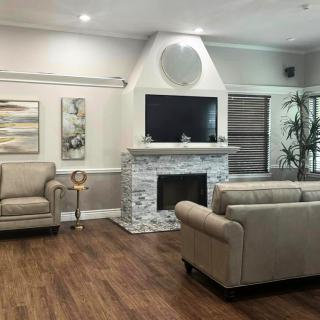 A modern living room with a fireplace, sofas, and a television set against a hardwood floor.