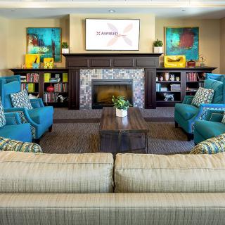 A cozy living room with a modern fireplace, comfortable seating, and colorful decor.