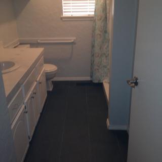 A bathroom with a vanity, sink, toilet, and shower curtain.