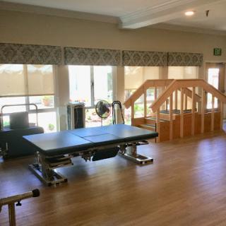 A spacious and well-lit physical therapy room equipped with exercise equipment and a wooden ramp for rehabilitation.