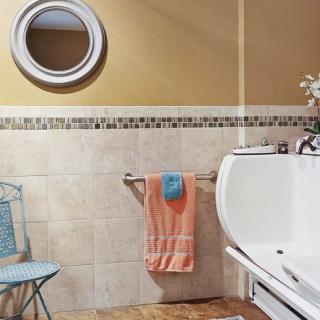 A cozy bathroom with a round mirror, towel rack, and bathtub.