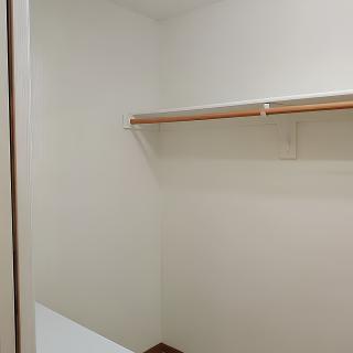 An empty closet with a wooden shelf and hanging rod.