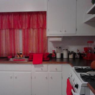 A cozy kitchen with red accents and white cabinetry.