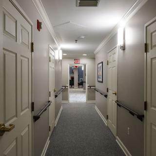 A well-lit hallway with multiple doors and a carpeted floor.