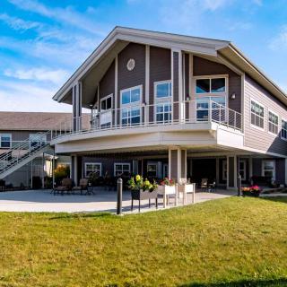 A modern residential building with large windows and a well-maintained lawn under a clear blue sky.