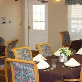A neatly set dining table with chairs in a well-lit room.