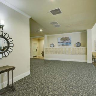 A hallway with a decorative mirror, carpeting, and mailboxes on the wall.