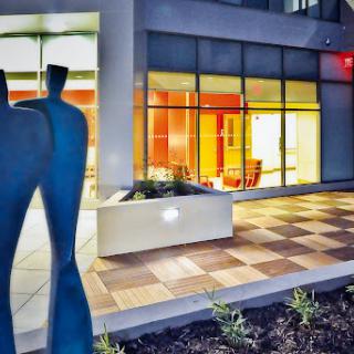A contemporary outdoor sculpture stands in front of a modern building, showcasing a blend of art and architecture.