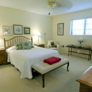A cozy bedroom with a neatly made bed, wooden furniture, and soft lighting.
