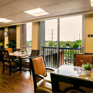A cozy dining area with large windows, filled with natural light and decorated with plants.
