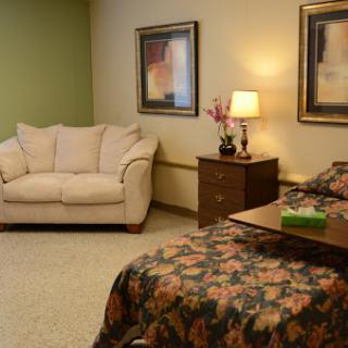 A cozy room featuring a bed with a floral patterned cover, a comfortable sofa, and decorative wall art.