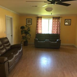 A cozy living room with yellow walls, featuring two leather sofas and a window with patterned curtains.