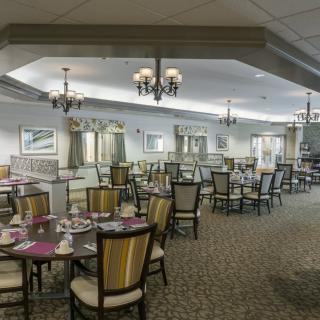 A spacious restaurant dining area with elegantly set tables and chandeliers.