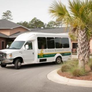 A white van parked on a curved driveway in front of a building with palm trees.