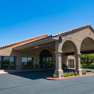A commercial building entrance with an awning and adjacent parking lot under a clear blue sky.
