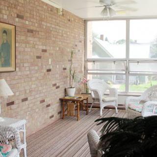 A cozy sunroom with wicker furniture and large windows allowing natural light to illuminate the space.