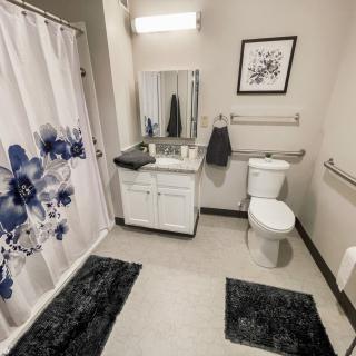A modern bathroom with a floral shower curtain, white vanity, and decorative touches.