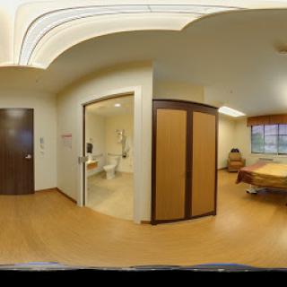A spacious hospital room featuring a bed and an adjoining bathroom.