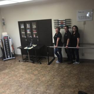 A group of people in an office setting create a fun optical illusion by appearing to levitate a broom.