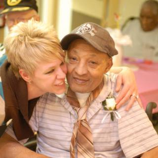 A heartwarming moment between a caregiver and an elderly resident, sharing smiles and affection.