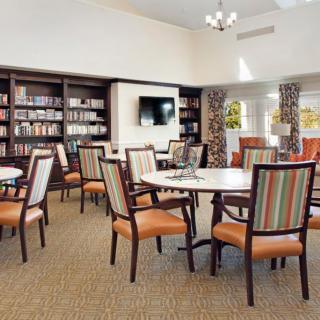 A cozy reading room with bookshelves, tables, and chairs.