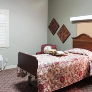 A cozy bedroom with a single bed and floral bedspread, complemented by a chair and decorative wall art.