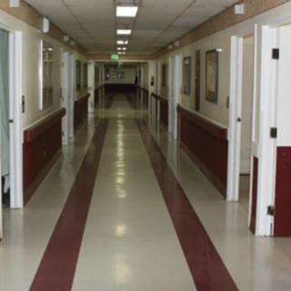 An empty hospital hallway with doors on either side.