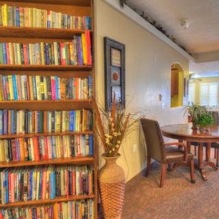 A cozy reading nook featuring a well-stocked bookshelf and a dining area, perfect for relaxation and gathering.