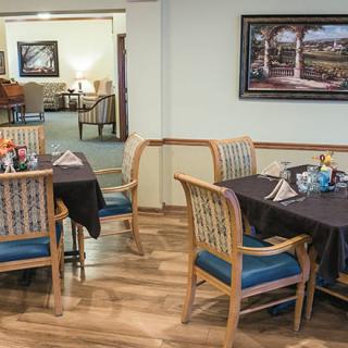 A cozy dining area with neatly arranged tables and chairs, featuring a decorative painting on the wall.