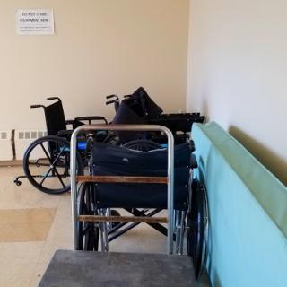 A row of wheelchairs parked against a wall in a healthcare facility.
